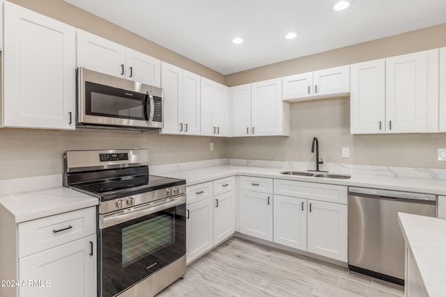 kitchen featuring white cabinetry, sink, light stone counters, and appliances with stainless steel finishes