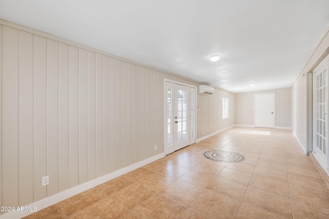 tiled spare room with a wall mounted AC, french doors, and wood walls