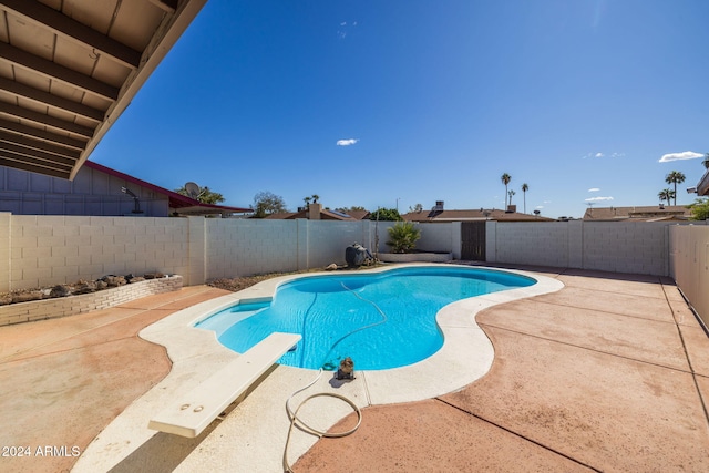 view of pool with a diving board and a patio area