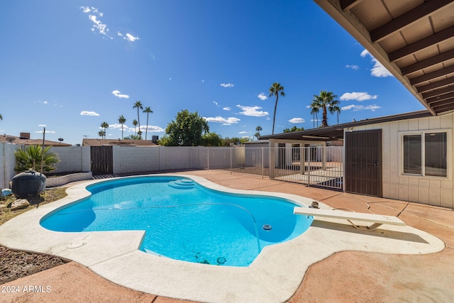 view of swimming pool featuring a patio and a diving board