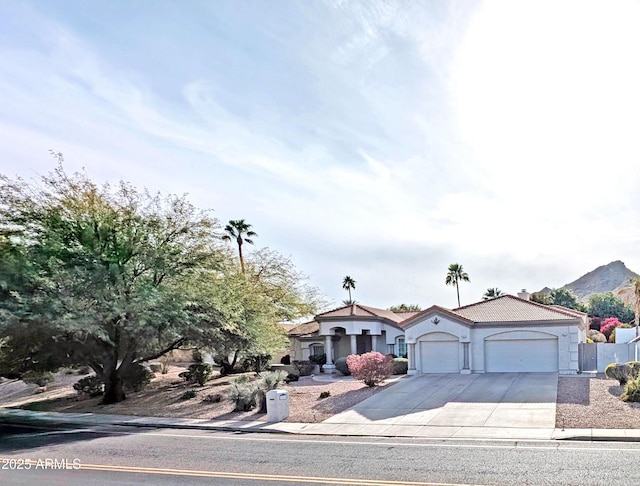 mediterranean / spanish home with driveway, a tiled roof, an attached garage, and stucco siding