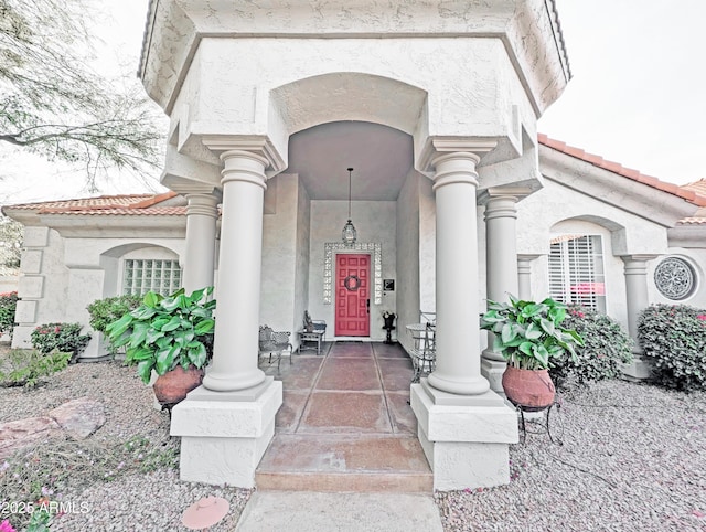 view of exterior entry featuring a tiled roof and stucco siding