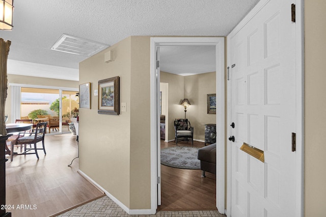 hall featuring light hardwood / wood-style floors and a textured ceiling