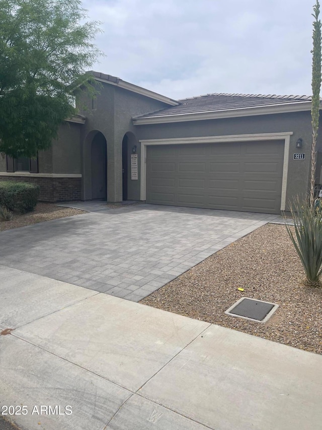 3211 W Pollack St, Phoenix, AZ 85041 - view of front facade featuring decorative driveway, a garage, and stucco siding