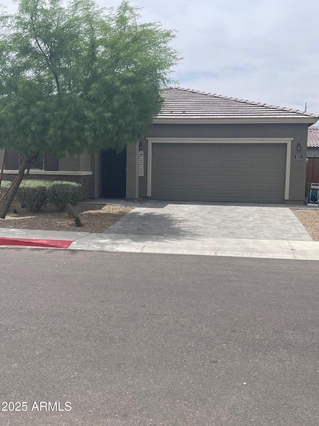 3211 W Pollack St, Phoenix, AZ 85041 - view of front of home featuring an attached garage, driveway, a tile roof, and stucco siding