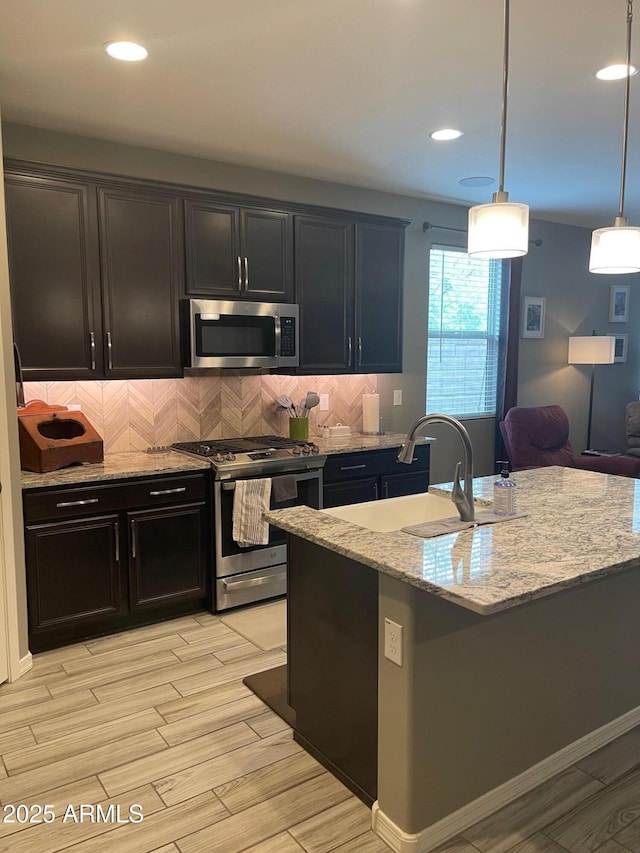 3211 W Pollack St, Phoenix, AZ 85041 - kitchen featuring appliances with stainless steel finishes, light stone countertops, backsplash, light wood-type flooring, and pendant lighting