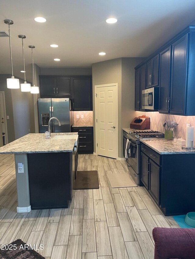 3211 W Pollack St, Phoenix, AZ 85041 - kitchen with stainless steel appliances, wood tiled floors, light stone counters, a center island with sink, and recessed lighting