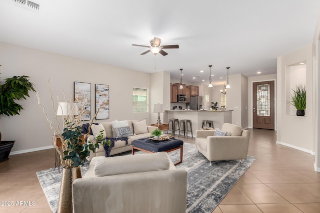 living area with light tile patterned floors, visible vents, baseboards, and ceiling fan