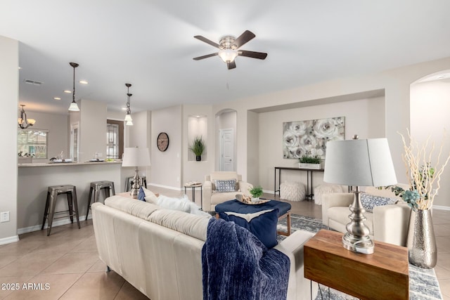 living area featuring arched walkways, light tile patterned floors, baseboards, and visible vents