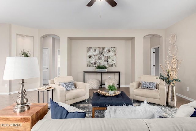 living area with arched walkways, ceiling fan, and baseboards