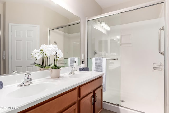 bathroom with double vanity, a stall shower, and a sink