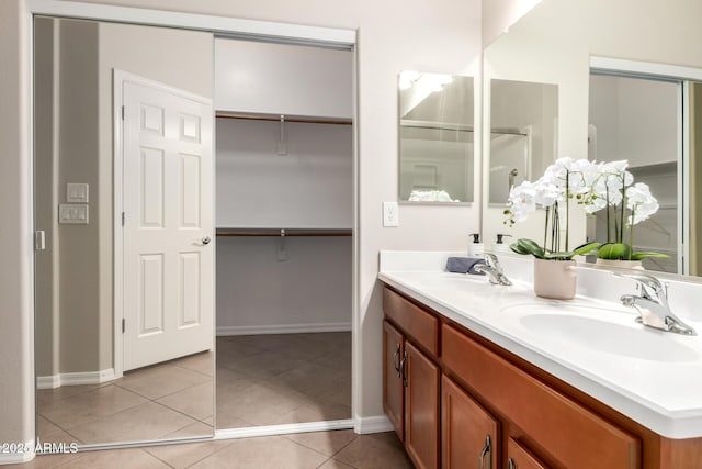 full bathroom featuring tile patterned flooring, double vanity, a walk in closet, and a sink