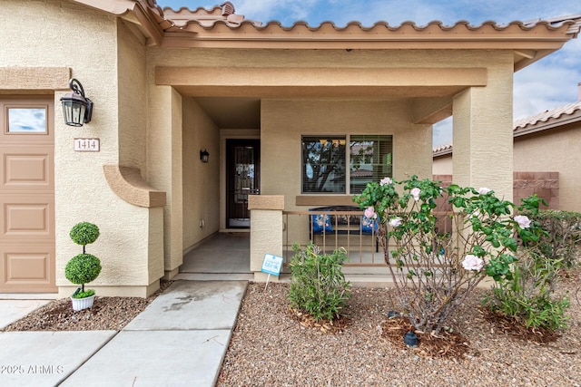 view of exterior entry featuring covered porch, stucco siding, and an attached garage