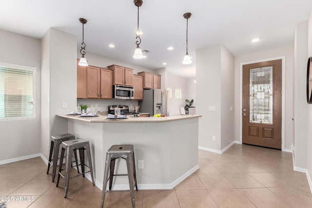 kitchen featuring light tile patterned floors, stainless steel appliances, a peninsula, and light countertops