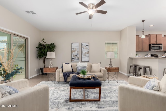 living room featuring ceiling fan, visible vents, baseboards, and light tile patterned flooring