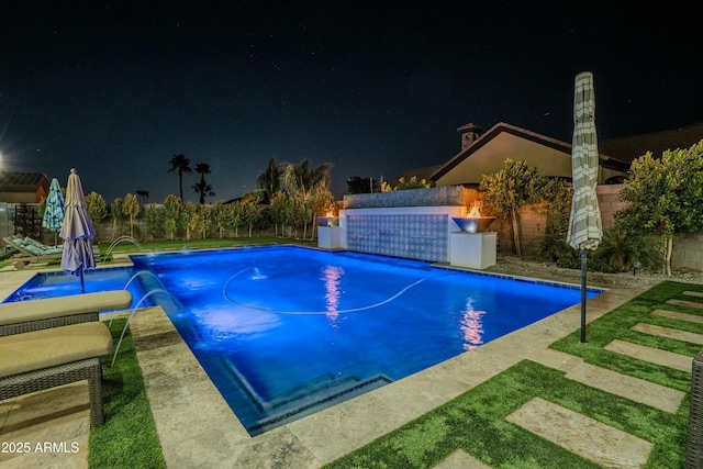 pool at twilight featuring pool water feature