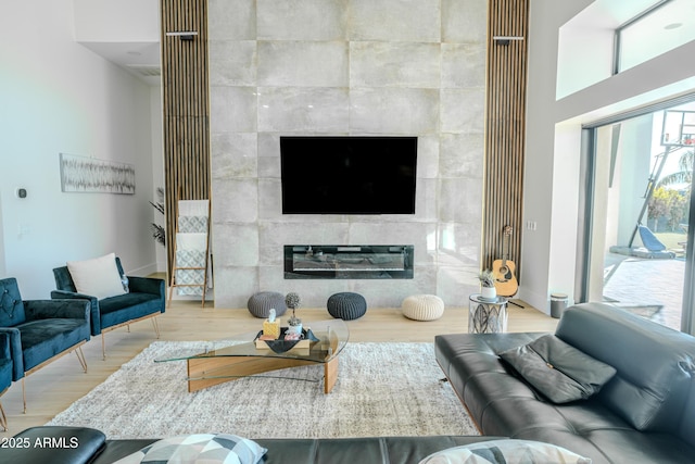 living room with hardwood / wood-style flooring, a tiled fireplace, tile walls, and a wealth of natural light