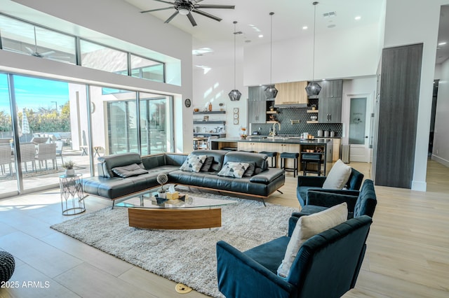 living room with a high ceiling, sink, and ceiling fan