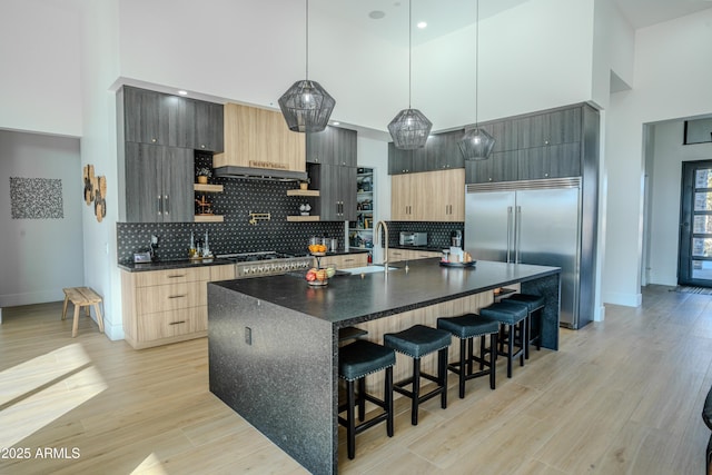 kitchen featuring pendant lighting, a kitchen island with sink, stainless steel appliances, and a high ceiling