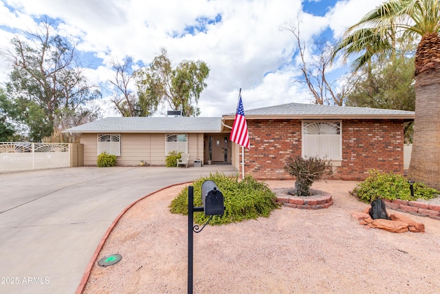 ranch-style home with driveway, brick siding, and fence