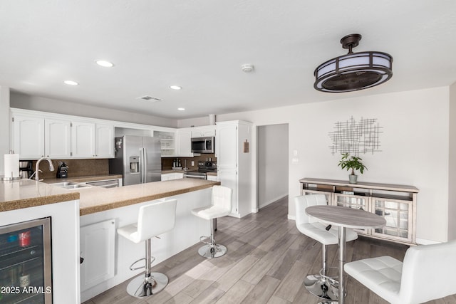 kitchen featuring wine cooler, a sink, visible vents, appliances with stainless steel finishes, and tasteful backsplash