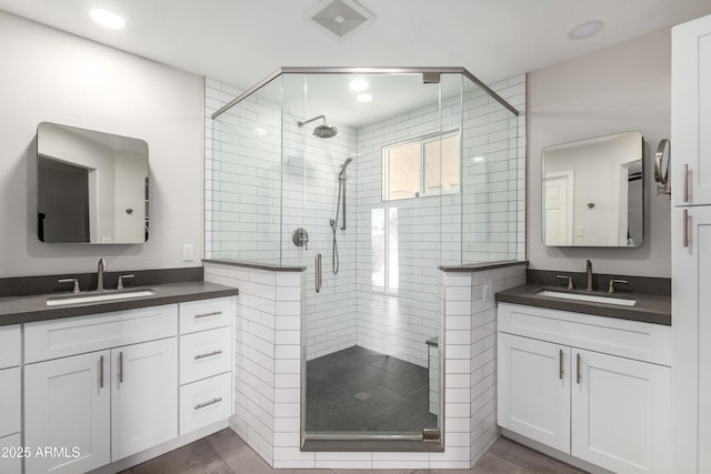 bathroom with a stall shower, two vanities, a sink, and recessed lighting