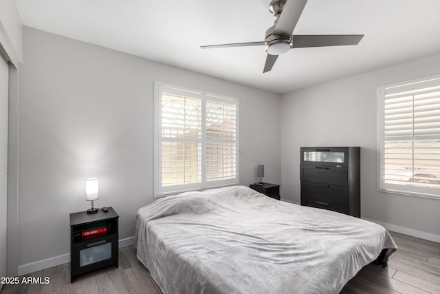 bedroom featuring a ceiling fan, baseboards, and wood finished floors