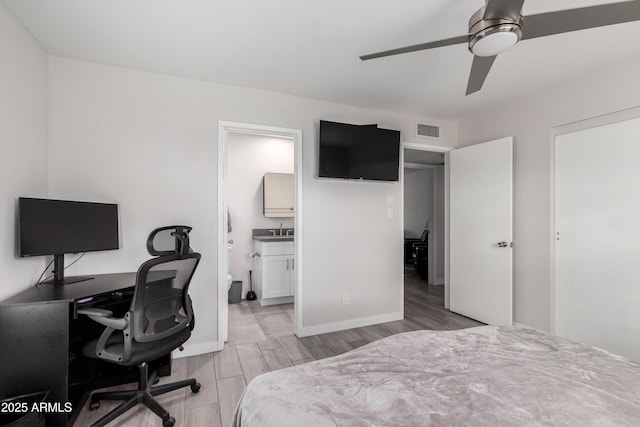 bedroom featuring wood finish floors, visible vents, connected bathroom, a sink, and baseboards