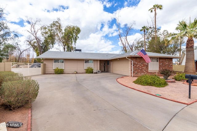 ranch-style home featuring a garage, concrete driveway, brick siding, and fence