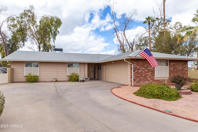 ranch-style home featuring a garage, fence, concrete driveway, and brick siding