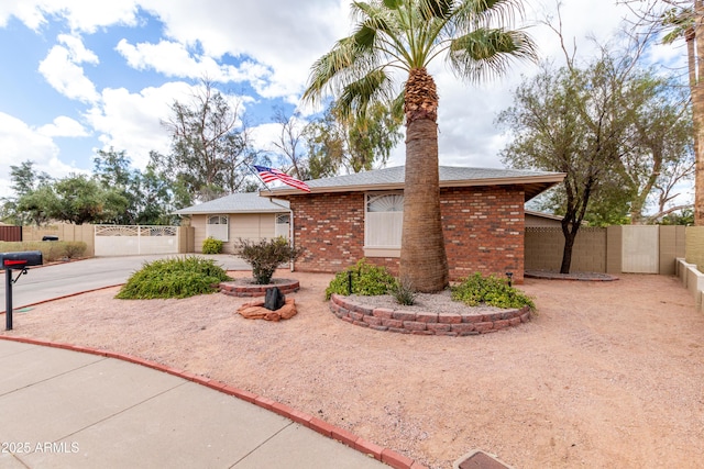 view of front of home featuring brick siding, fence, driveway, roof with shingles, and a gate