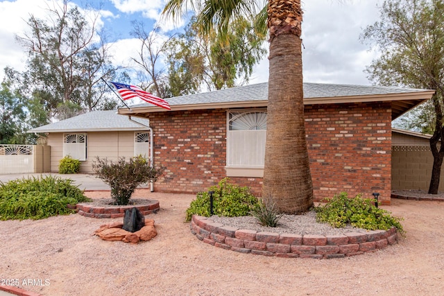 ranch-style home with brick siding, roof with shingles, a patio area, and fence