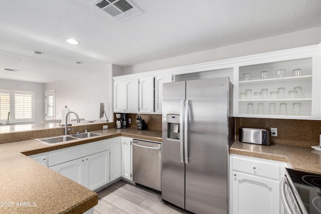 kitchen featuring stainless steel appliances, visible vents, a sink, and white cabinetry