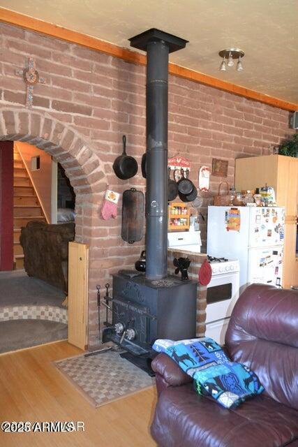 3733 Del Contento Rd, Snowflake, AZ 85937 - living area featuring a wood stove, wood finished floors, brick wall, and stairs