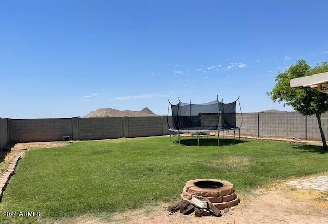 5881 E Sunrise Cir, Florence, AZ 85132 - view of yard with an outdoor fire pit, a trampoline, and a fenced backyard