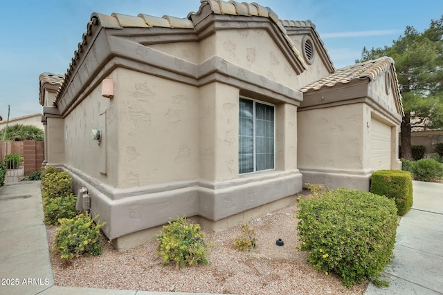 view of property exterior with a garage, stucco siding, and a tile roof