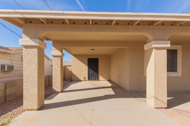 entrance to property with a wall unit AC and a patio