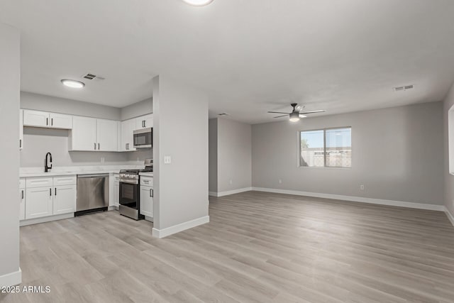 kitchen with sink, light hardwood / wood-style flooring, ceiling fan, appliances with stainless steel finishes, and white cabinets