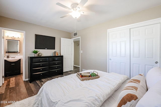 bedroom with dark wood-type flooring, sink, ensuite bath, ceiling fan, and a closet