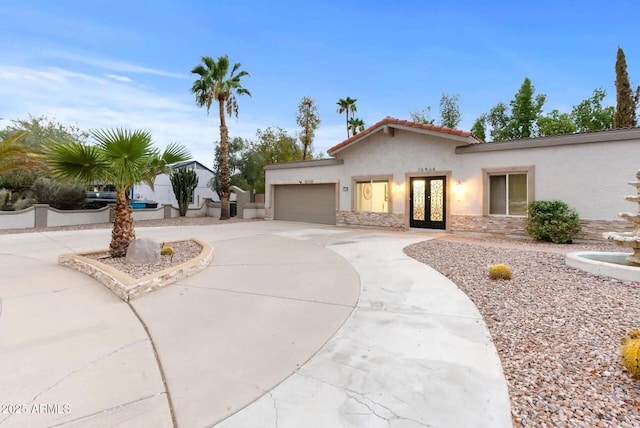 16436 N 64th Pl, Scottsdale, AZ 85254 - mediterranean / spanish house with stucco siding, curved driveway, french doors, an attached garage, and stone siding