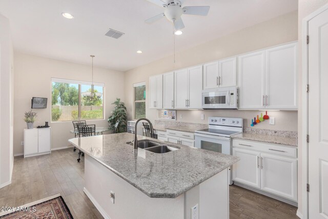 kitchen with ceiling fan, an island with sink, white appliances, sink, and dark hardwood / wood-style floors