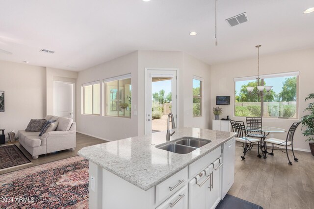 kitchen with white cabinetry, light hardwood / wood-style flooring, light stone countertops, pendant lighting, and sink