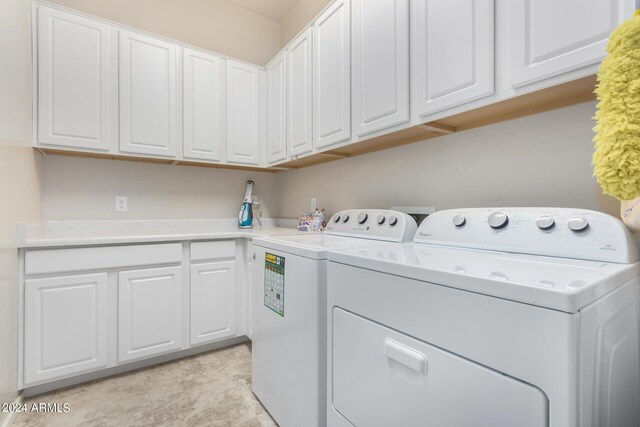 clothes washing area with washing machine and dryer, cabinets, and light tile patterned floors