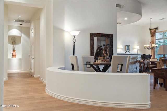 hallway featuring an inviting chandelier and light hardwood / wood-style flooring