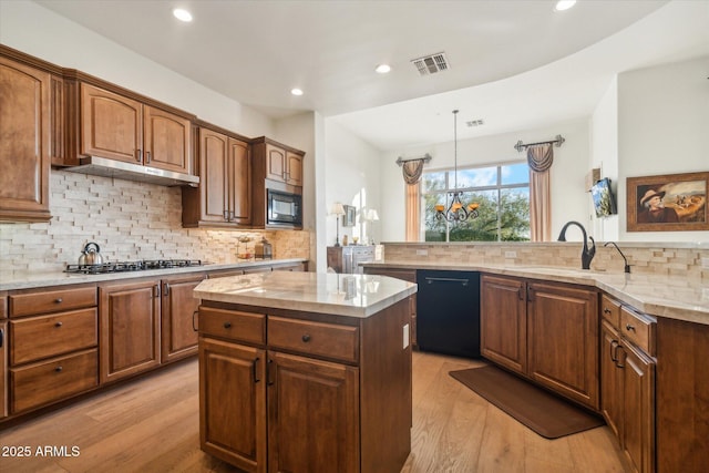 kitchen with a center island, light hardwood / wood-style flooring, kitchen peninsula, decorative backsplash, and black appliances