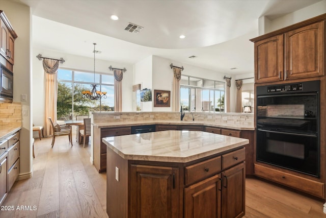 kitchen featuring double oven, backsplash, a center island, light hardwood / wood-style floors, and kitchen peninsula