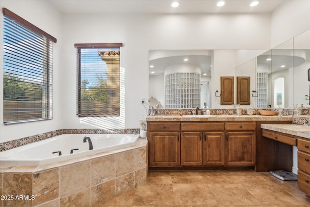 bathroom with vanity and tiled bath