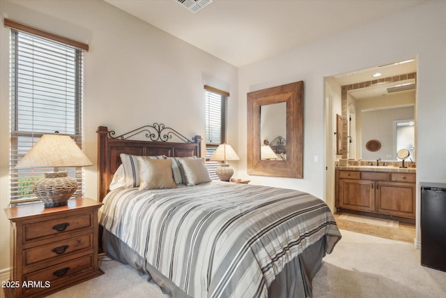 bedroom featuring light colored carpet, ensuite bathroom, and sink