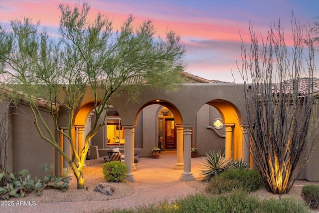 back house at dusk featuring a patio