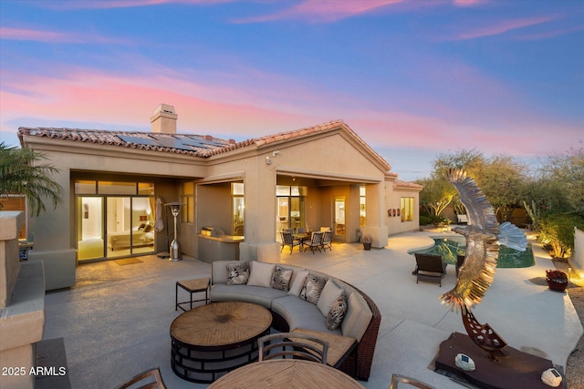 back house at dusk with a patio, an outdoor living space with a fire pit, and solar panels